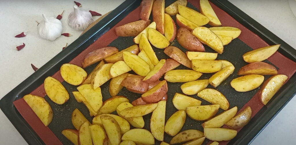 Картопля почищена дольками викладена на деко