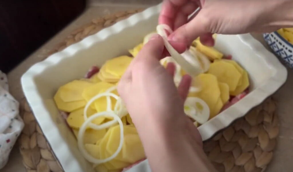 Картопля і цибуля викладена на м'ясо
