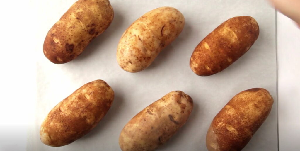 Сира неочищена картопля викладена на деко для запікання