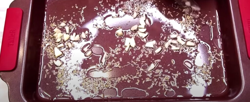 Деко змазане олією і з викладеним часником і травами на ньому