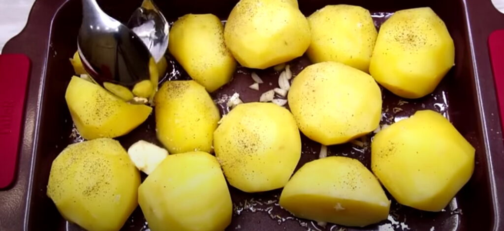 Картопля викладена на деко з часником, салом і олією