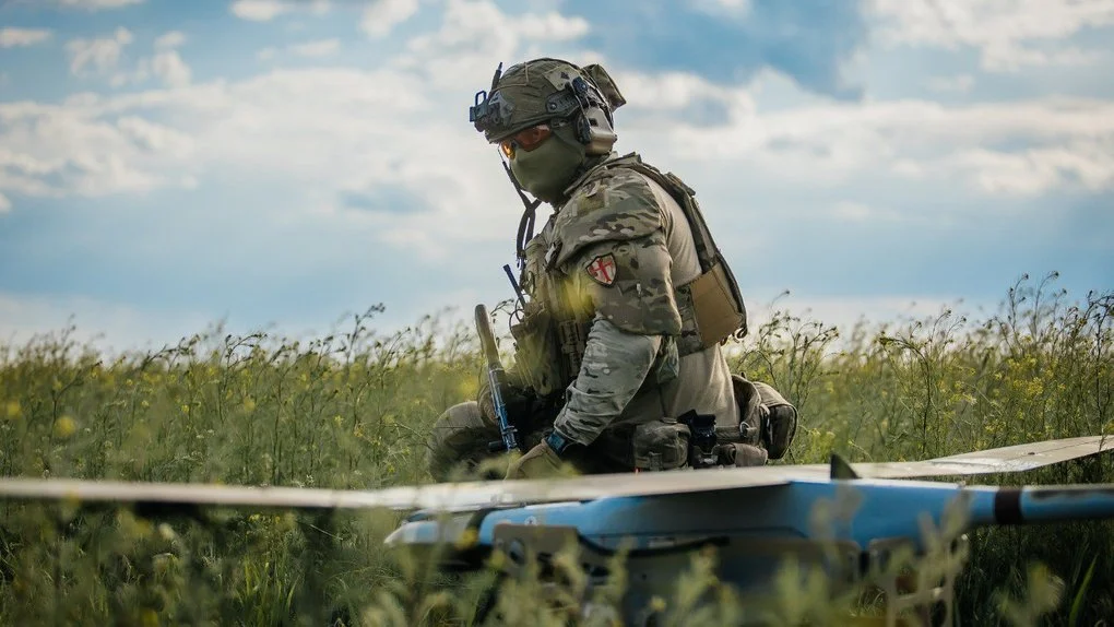 Військовий у повній амуніції з бпла посеред поля